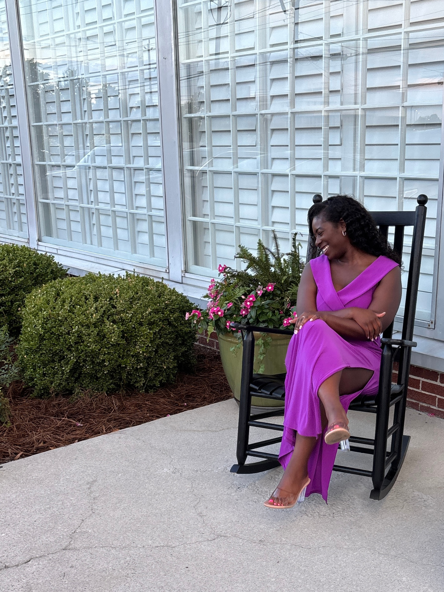 Moriah Davis laughing in a purple maxi dress while sitting in a black rocking chair