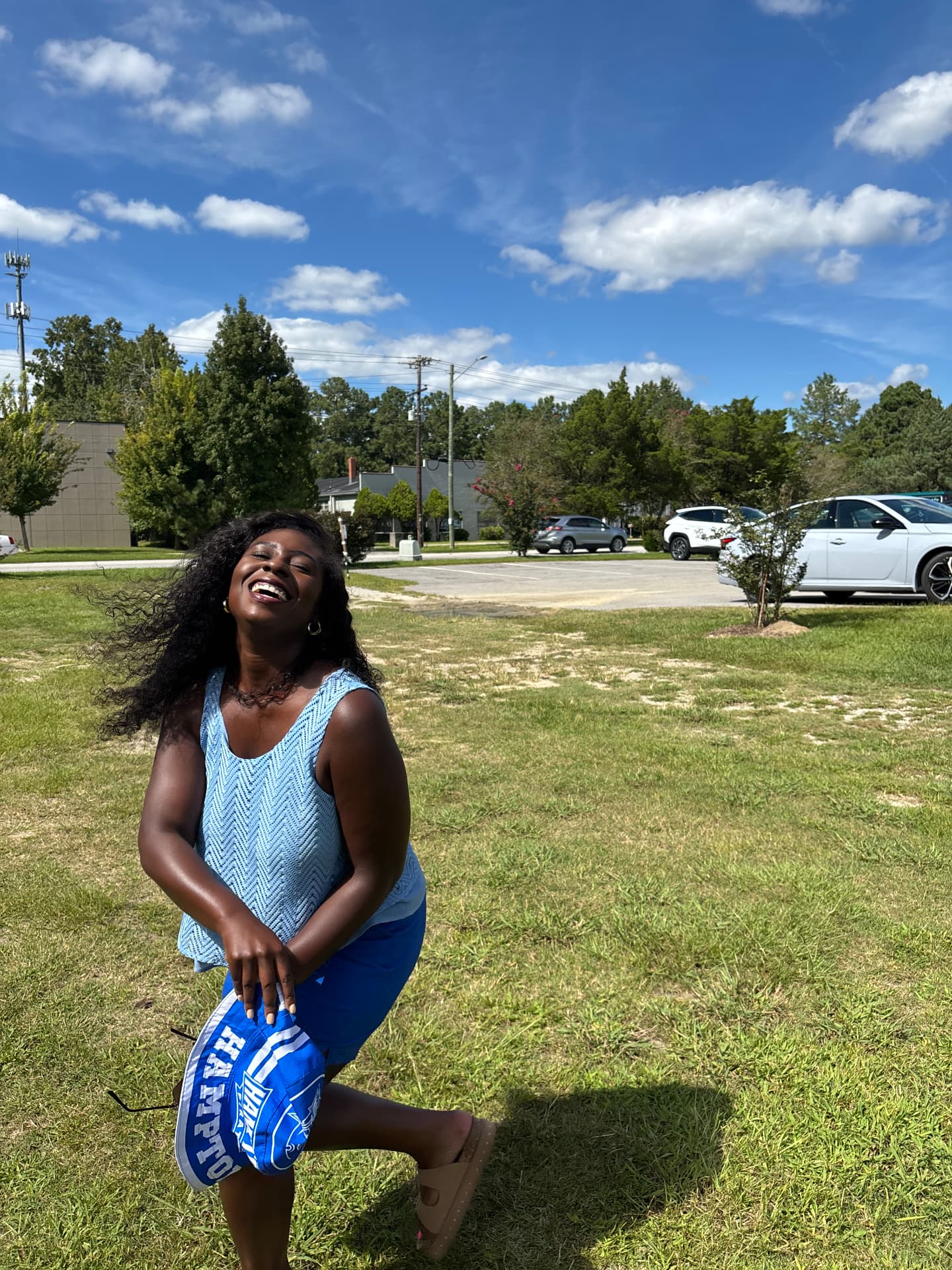 Moriah Davis laughing in the sunshine holding a Hampton hat