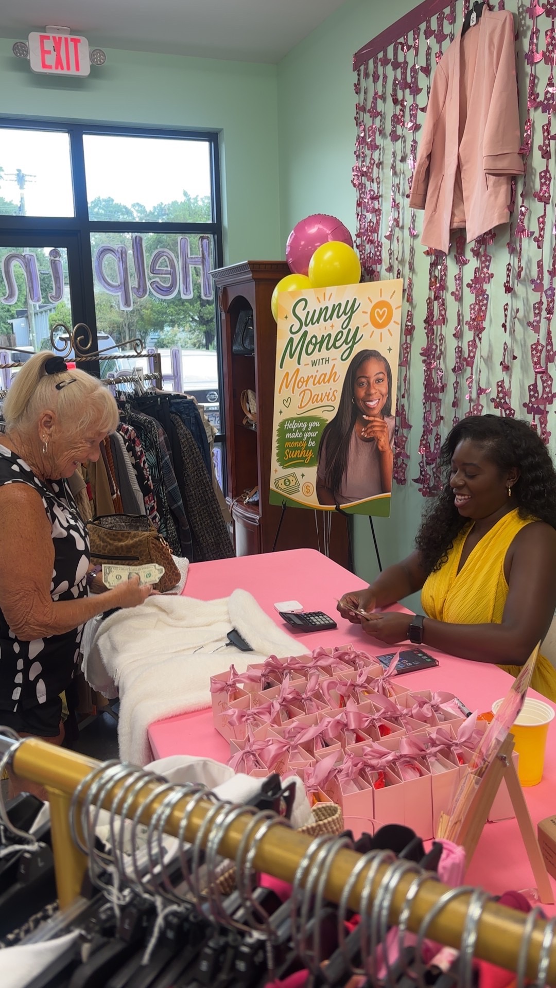 A shopper paying at the Moriah's Closet check-out table beside the Sunny Money sign